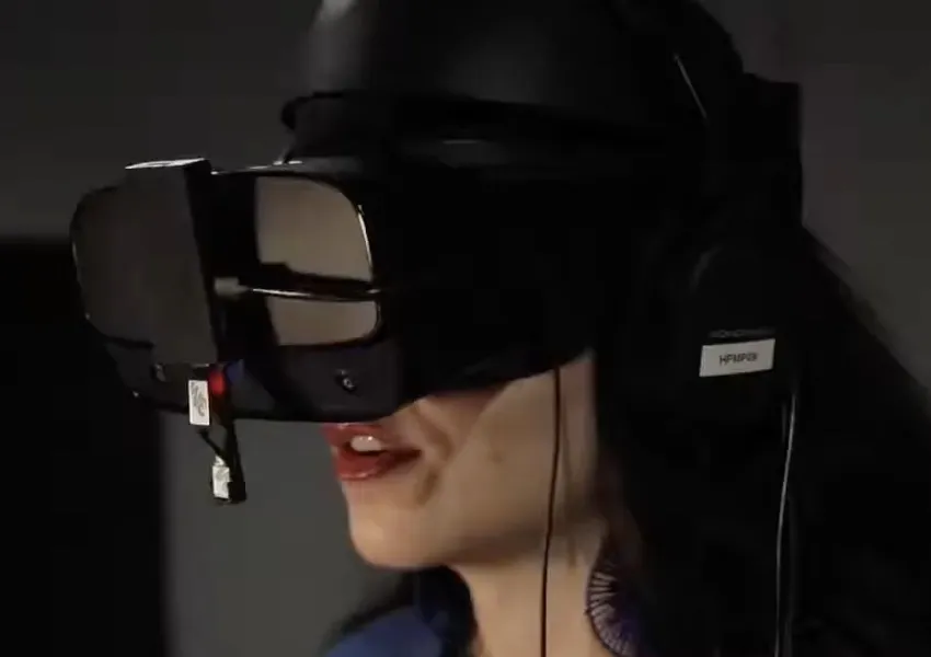 The finished build in use: a VR headset with a small camera board mounted under the front of it, angled down at the wearer’s face.