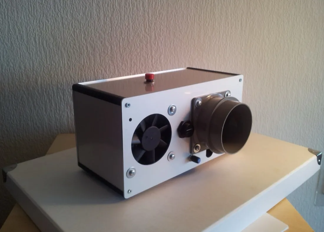 The same device from the side, showing the fan in one end panel and the wide grey duct it blows the scent out through.